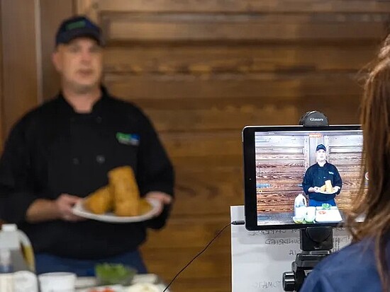 Chef demonstrating cooking skills in a live video class, showcasing delicious golden-brown dishes.